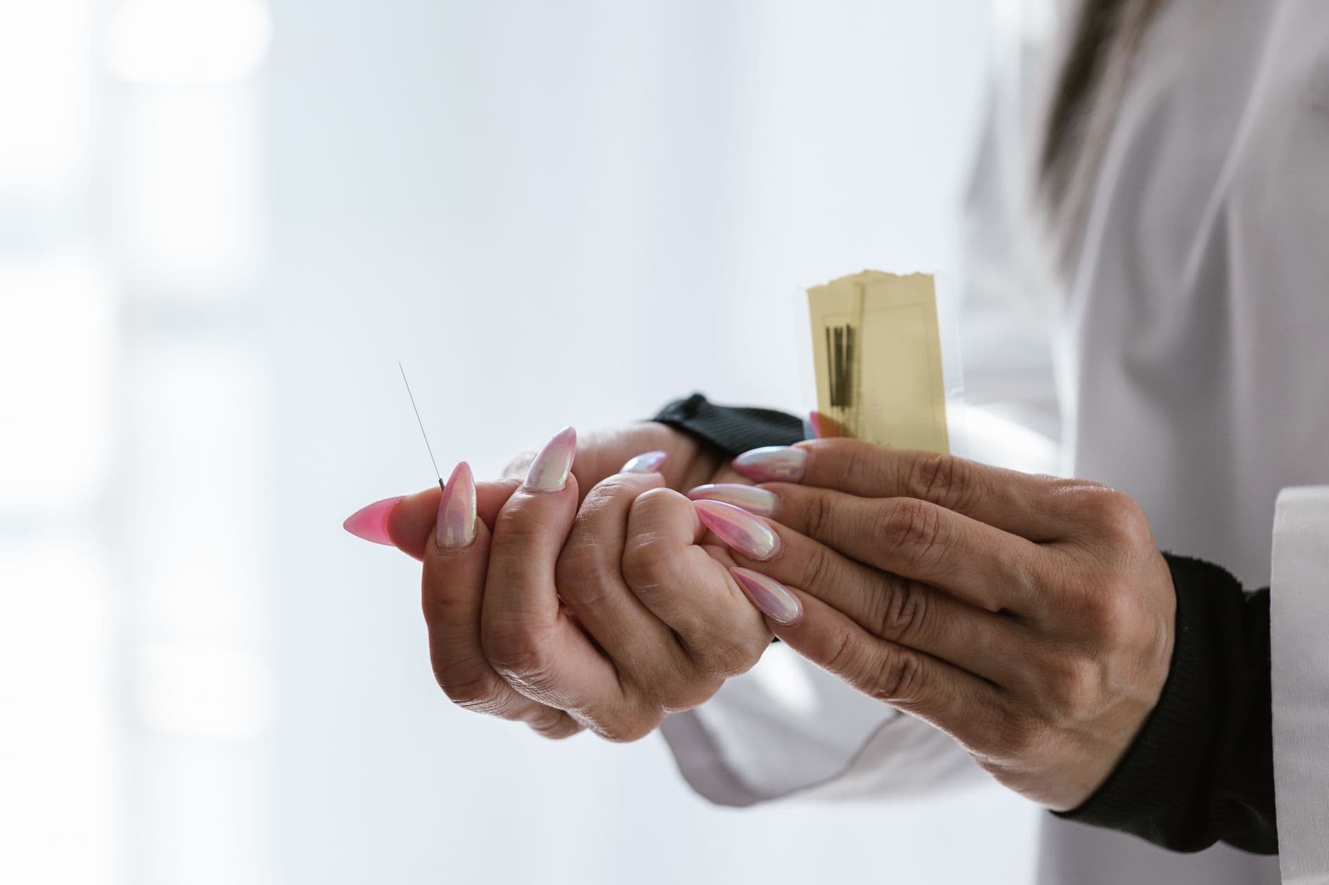 Acupuncturist hands holding acupuncture needles